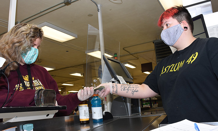 A cashier at the Commissary at Dugway Proving Ground gives a customer change, from one gloved hand to another. Photo by Al Vogel, Dugway Public Affairs.