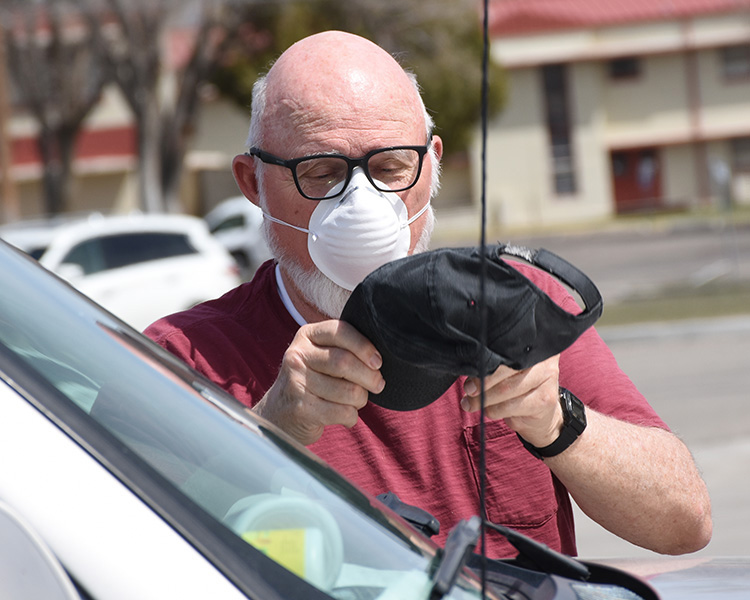 After adjusting his mask, a patron of the Commissary at Dugway Proving Ground dons his hat. Photo by Al Vogel, Dugway Public Affairs.