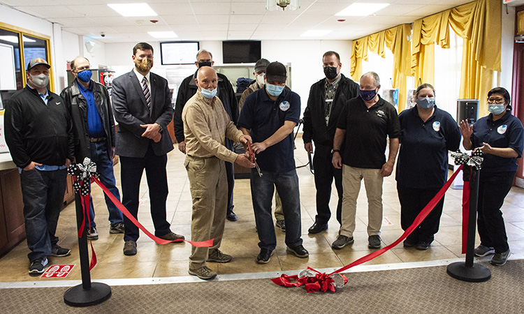 Dennis Nichols, chief of the Business and Recreation Division, and Jinky Tulabot, food and beverage manager, cut the red ribbon March 8, 2021 to reopen the Community Club in English Village. Of course, everyone is wearing a mask. Though open, the club offers no indoor seating, it is takeout only. Photo by Al Vogel, Dugway Public Affairs