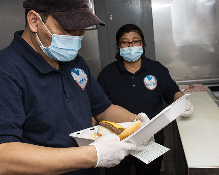 Jinky Tulabot, food and beverage manager, and the Community Clubs new cook, Emily Greenland, prepare a burger March 8, 2021. Masks are worn by all food preparers and the public in the club. Photo by Al Vogel, Dugway Public Affairs