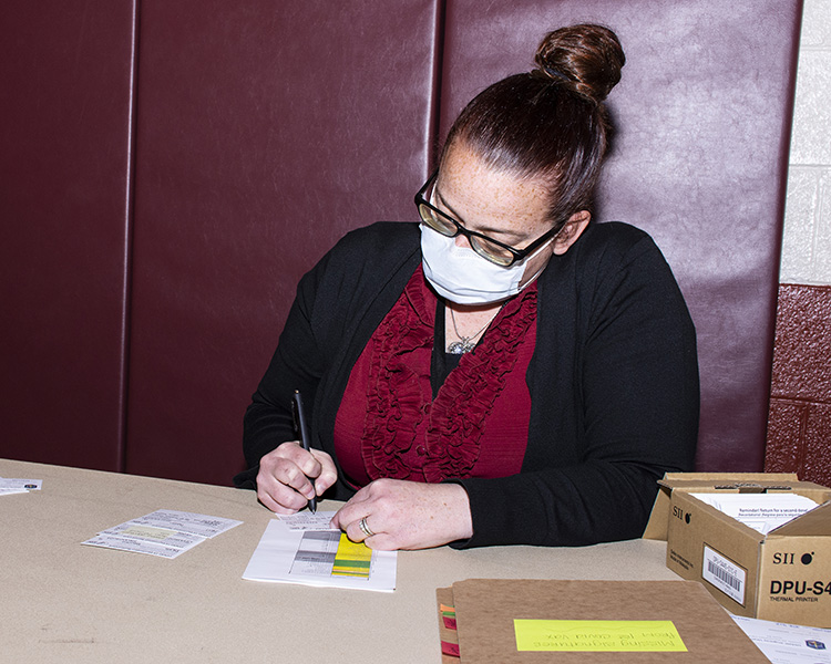 Heather Voss, Occupational Health Administrative Assistant, fills out Centers for Disease Control cards during a March 23, 2021 inoculation at Dugway Proving Ground. The cards, given to those who receive the coronavirus vaccine, indicate the vaccines manufacturer, date of inoculation and patients name. Photo by Al Vogel, Dugway Public Affairs