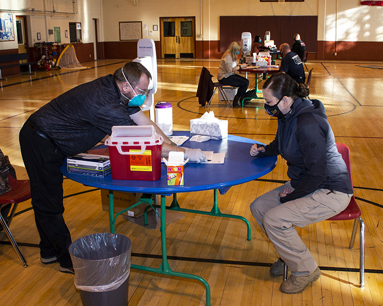 Sage Farmer, Occupational Health Technician, explains an aspect of the Moderna COVID-19 vaccine Jan. 19, 2021 to Courtney Montoya of EMS. This was the first of two inoculations for emergency personnel at Dugway Proving Ground, the second at least 28 days later. Photo by Al Vogel, Dugway Public Affairs