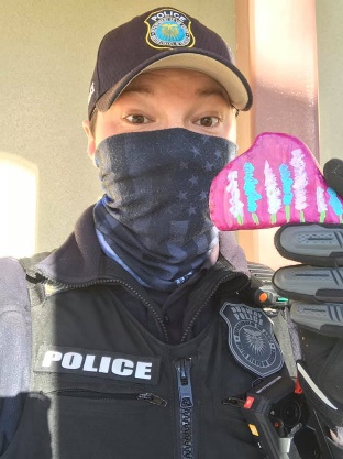 Police officer Justin Haymes poses with a painted rock he found while out on patrol.