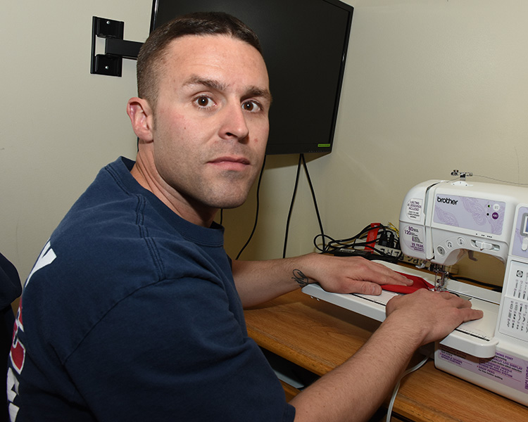 Lt. Brandon Roschewski of the Dugway Fire Department brought his sewing machine from home to make a few dozen facial masks for other firefighters. That done, he began making them for Dugway Security and Law Enforcement officers. He works alone in his room at the station. Photo by Al Vogel, Dugway Public Affairs.