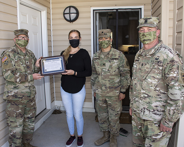 Summer Gabriel and her husband, Spc. Reef Gabriel recently began making cloth protective masks for Soldiers, medics, Emergency Services and others that run the risk of exposure to COVID-19.  Col. Scott Gould (left), Commander of Dugway Proving Ground, presented her with a DPG Certificate of Appreciation. Also presenting (right) was Command Sgt. Maj. Kyle Brinkman. She's made nearly 300, while her husband cuts the cloth and takes donations that are used to purchase supplies. Sgt. Andre' Wiggins and Spc. Alicia Stevens have also helped. Photo by Al Vogel, Dugway Public Affairs