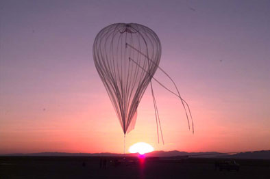 High-altitude weather balloon flying above the horizon in front of a pink and purple sunset during TREX testing at Dugway
