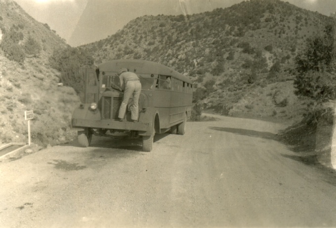 A 1940s Army bus gets a little tender care in the narrows on the west slope of the Stansbury Mountains. A concrete trough of drinking water, apparently from a spring, is seen at the left edge. Today, this road is Highway 199 over Johnson's Pass.