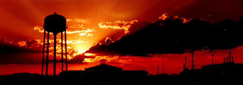 A sunset through clouds over Dugway water tower and buildings