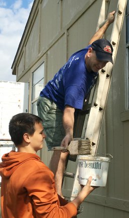 Lt. Col. Michael C. Firmin reaches for more paint in bucket held by Nathanial Eschmann, son of Cheryl Seymour