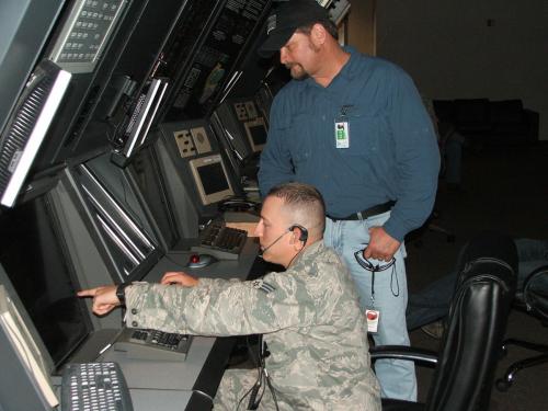 Senior Airman Kyle Causey gives his uncle, Mark Sury, a quick overview of the duties of an air traffic controller