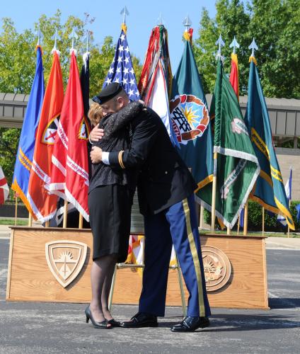 Mari Meyer, widow of retired Maj. Gen. Stew Meyer, embraces OTC commander Col. Scott Spellmon