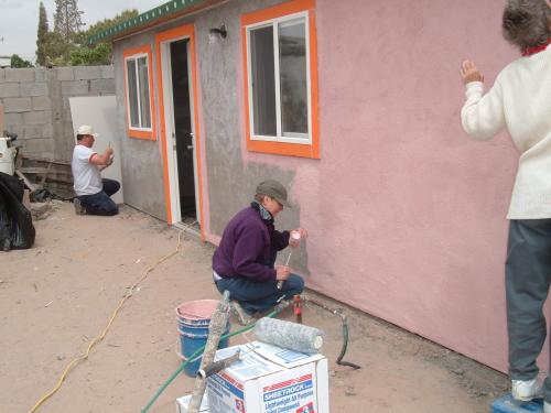 Mike Apodaca, left, paints exterior of house