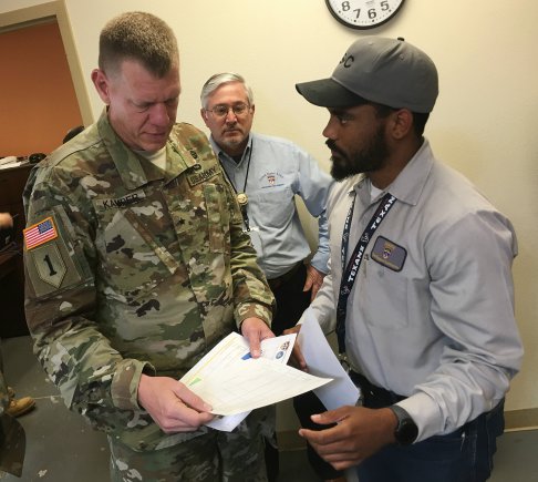 Fred Jones (right) shows test data collection sheets to Brig. Gen. Kenneth L. Kamper as Mitch Hickman listens in.