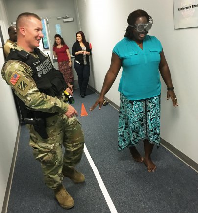 Staff Sgt. Kevin W. Nyman helps guide Vanessa Y. Millett as she navigates a field sobriety test while wearing 'drunk goggles'