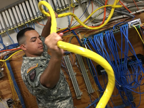 Cable installer pulls fiber optic cable through conduit
