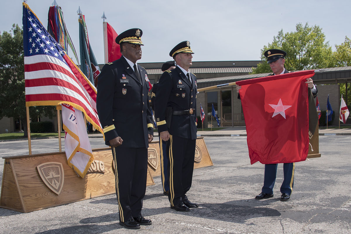 Command Sgt. Maj. Jason Schmidt (right) uncases Army's newest one-star general officer flag after Col. John Ulrich (center) is promoted to brigadier general (photo by Larry Furnace, OTC Test and Documentation Team)